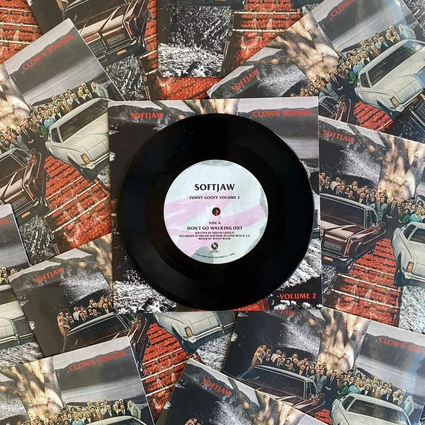 A black 7-inch vinyl record labeled 'SOFTJAW' with a barcode, surrounded by various album covers.
