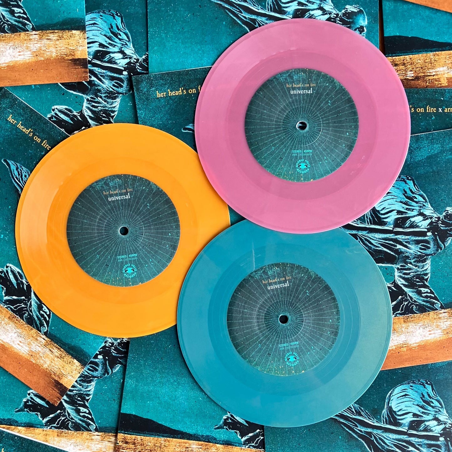 Three vinyl records with colorful covers on a textured surface