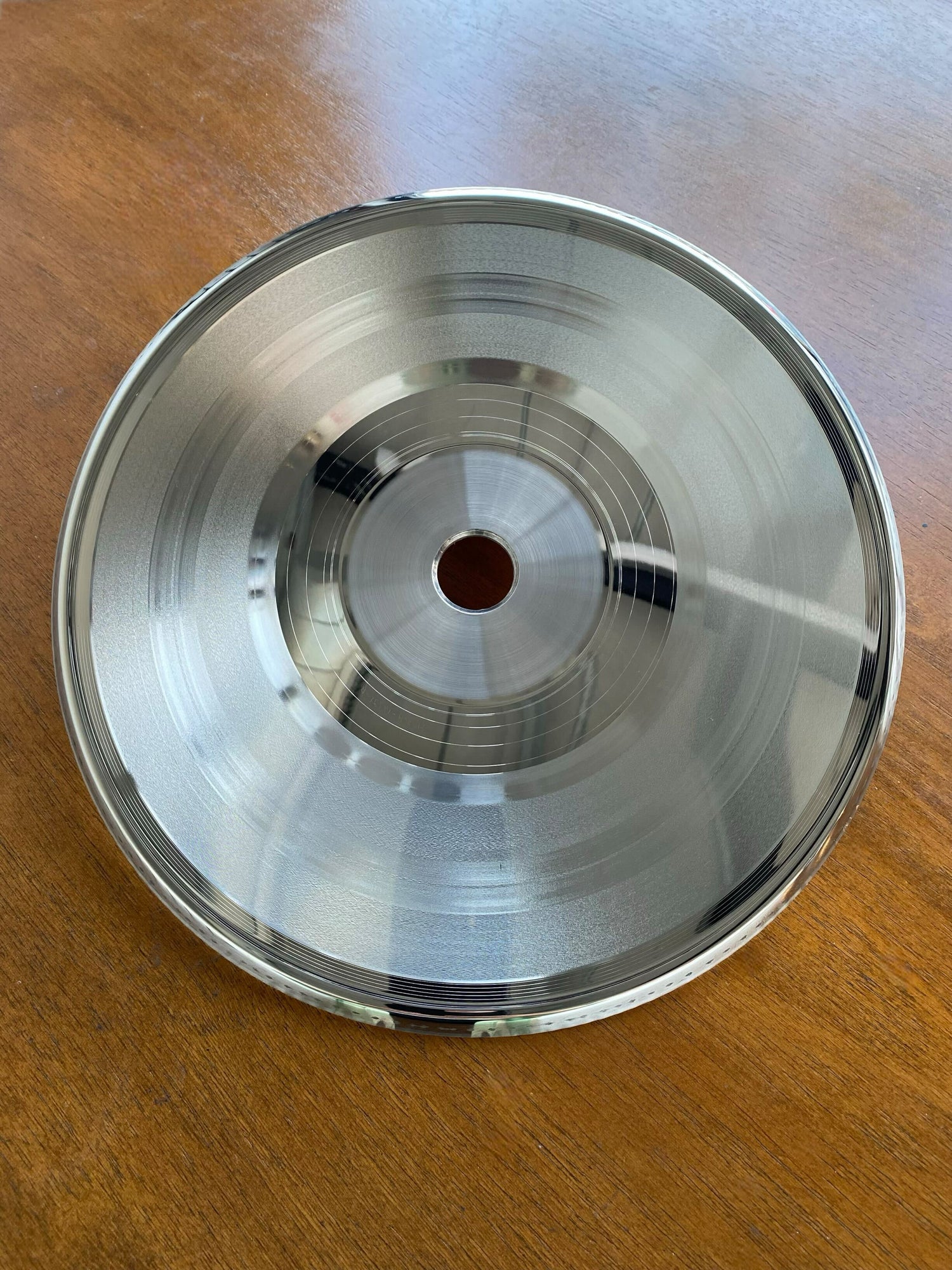 Metal stamper for vinyl record pressing on wooden table at Hellbender Vinyl