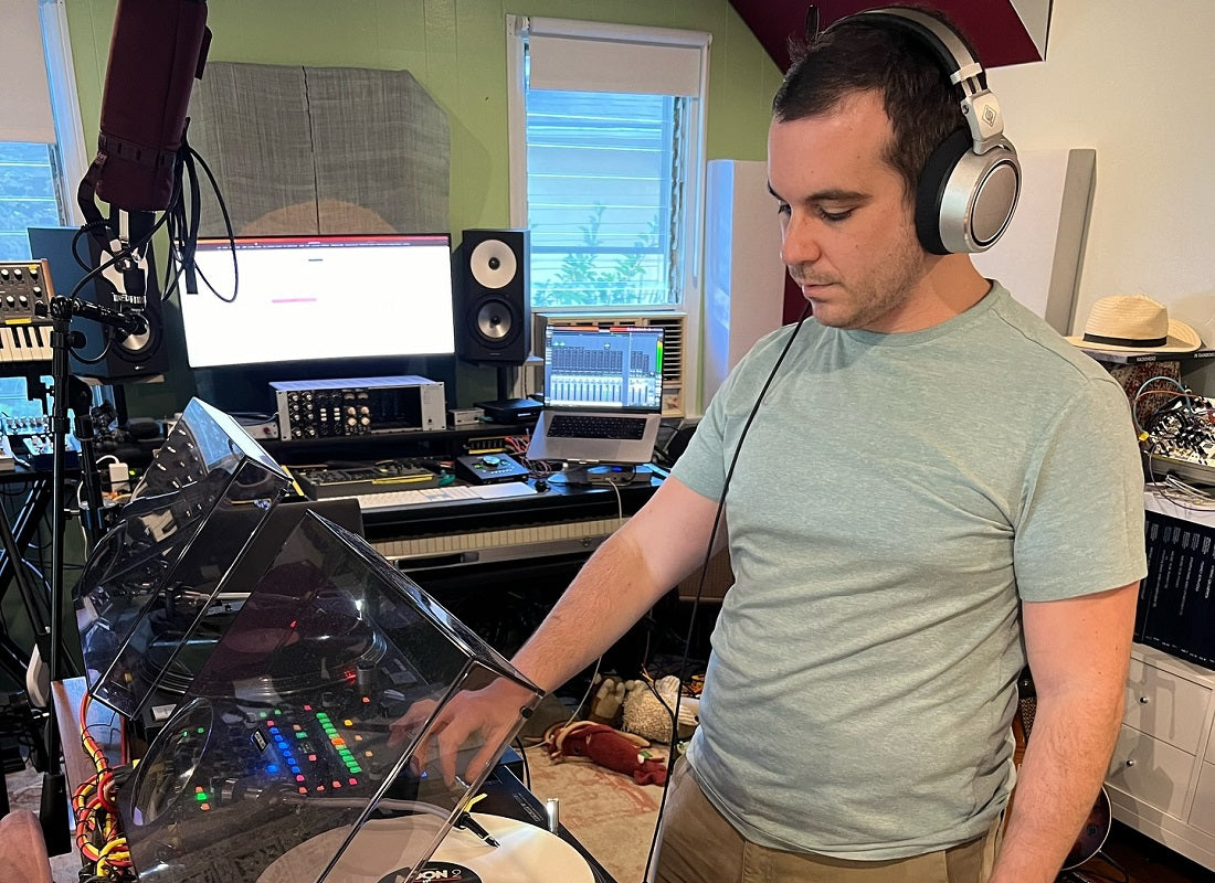 Person in a home studio setting with audio equipment and computer monitors.