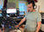 Person in a home studio setting with audio equipment and computer monitors.