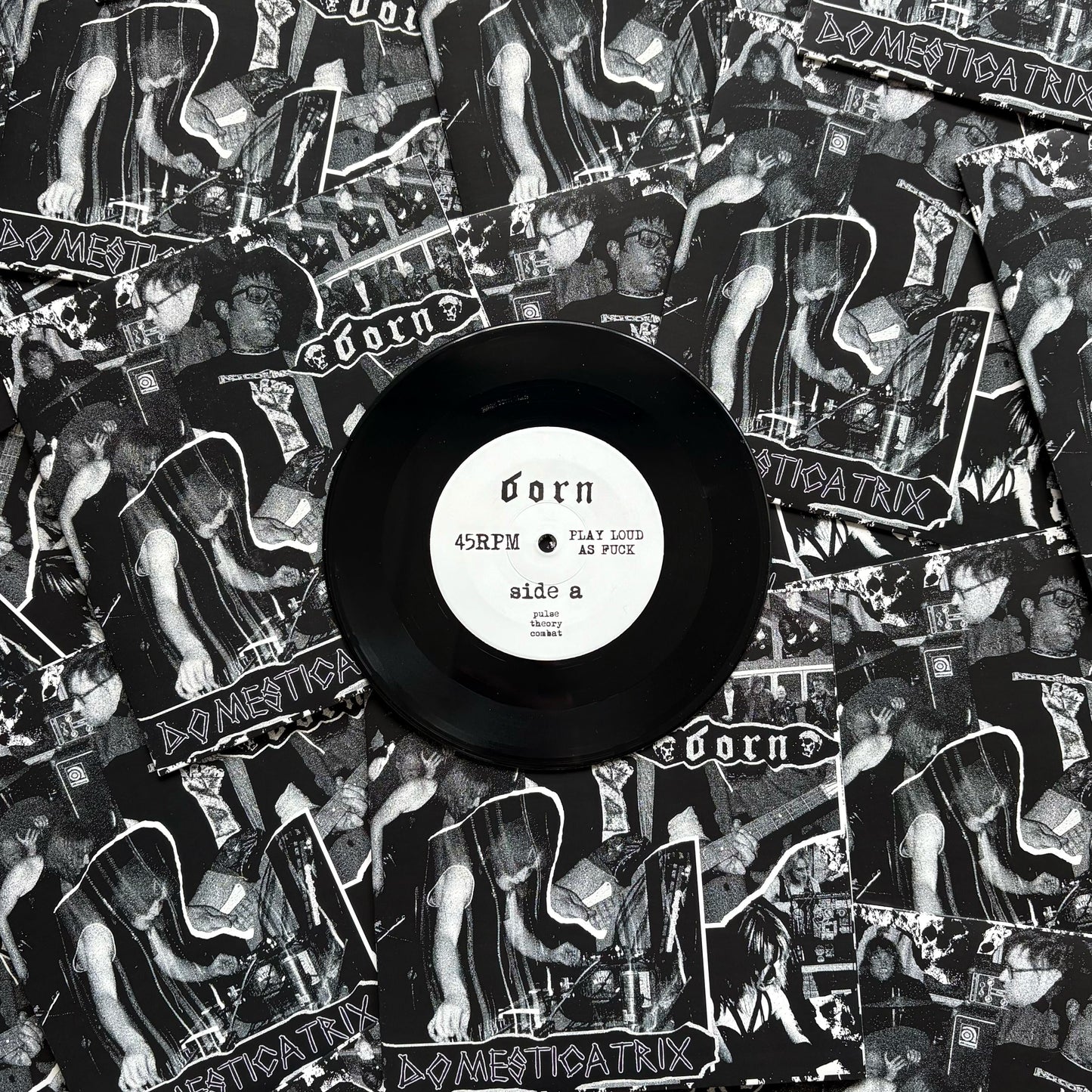 Vinyl record with a black label on top of a collage of album covers featuring a band.