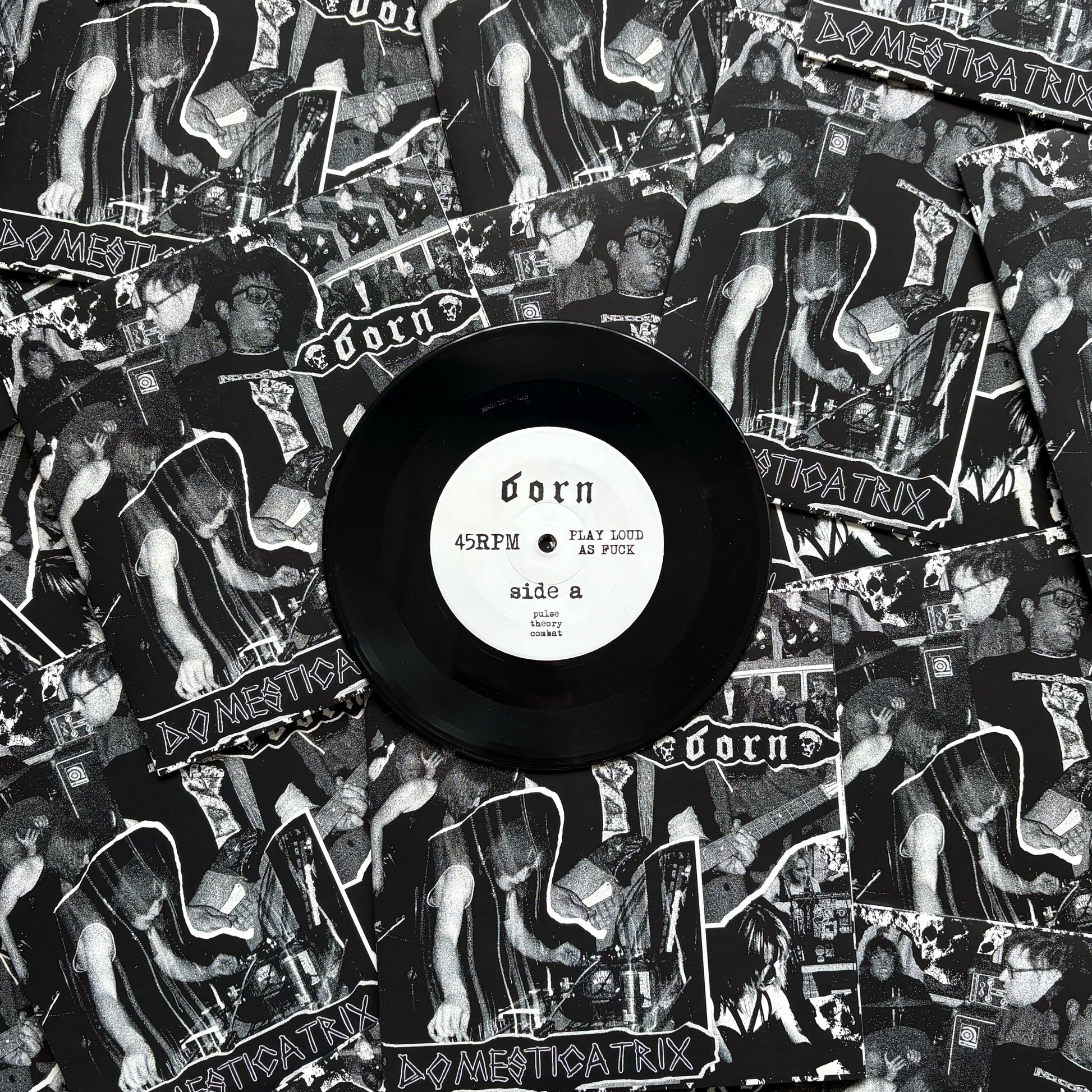 Vinyl record with a black label on top of a collage of album covers featuring a band.