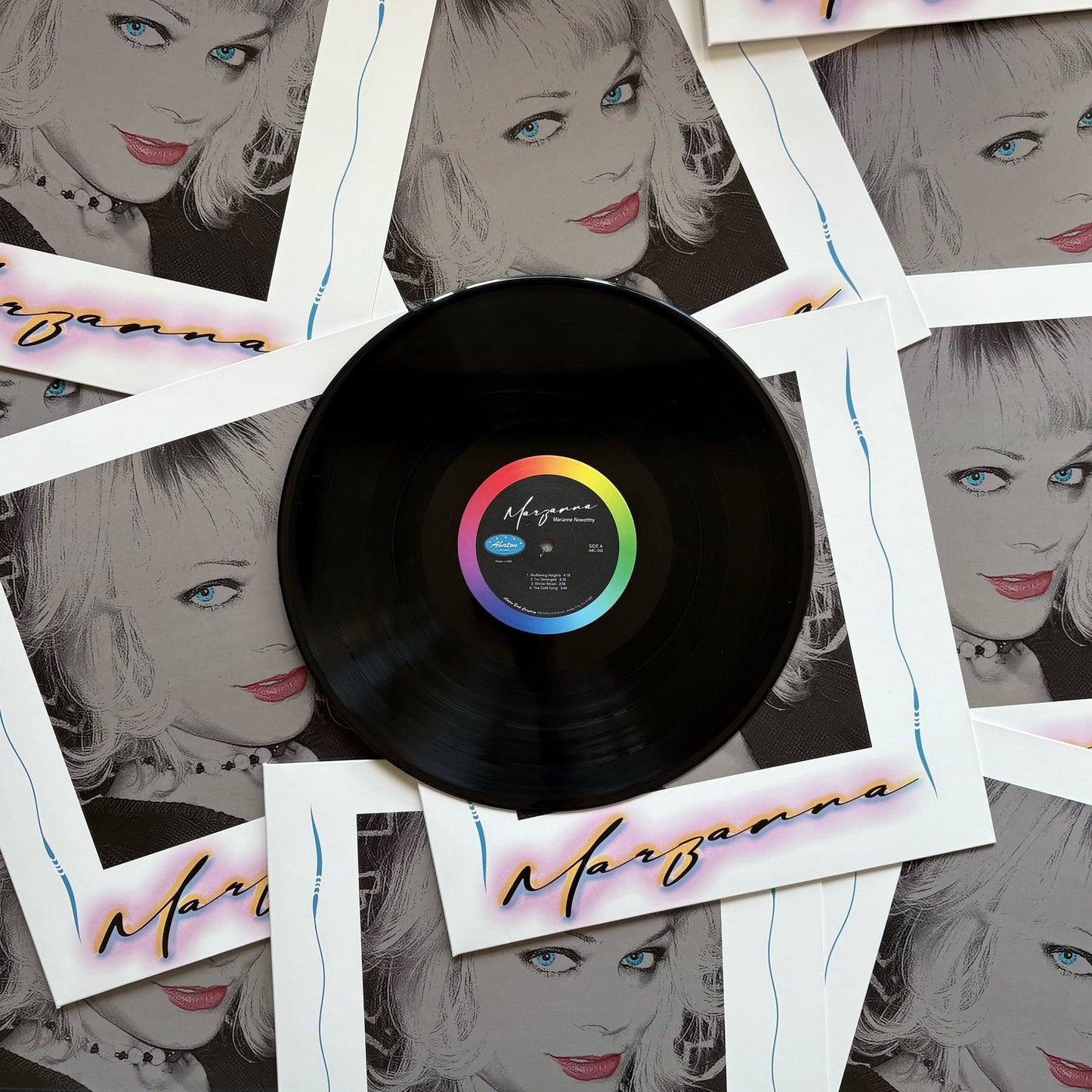 Vinyl record with a colorful label surrounded by Polaroid-style images of a woman's face.