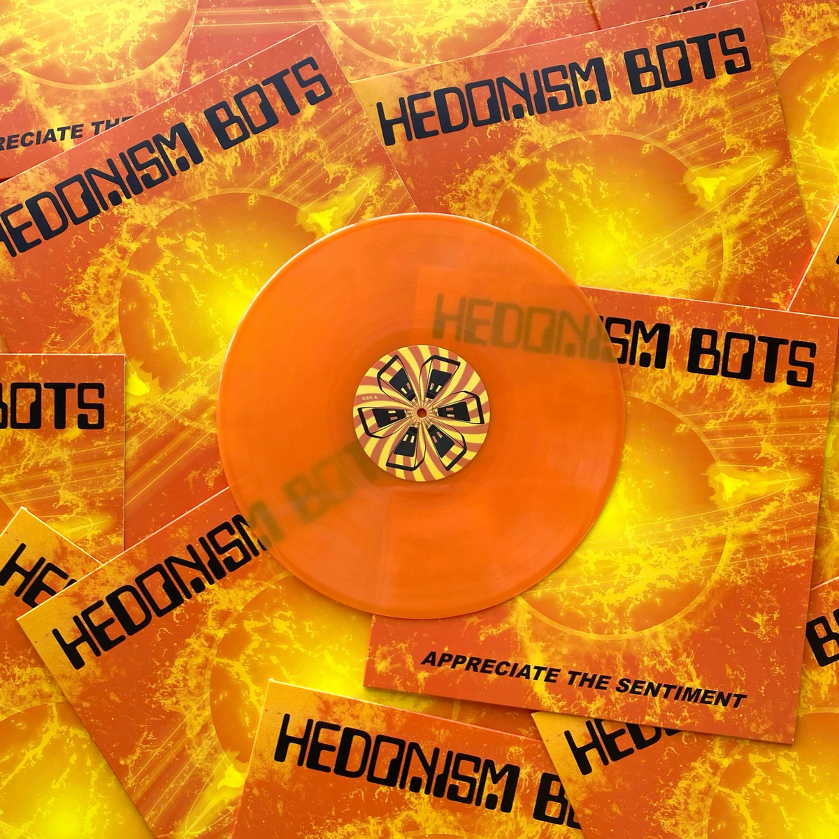 Clear hazy orange vinyl record with a gold center and 'Hedonism Bots' branding on a matching background.