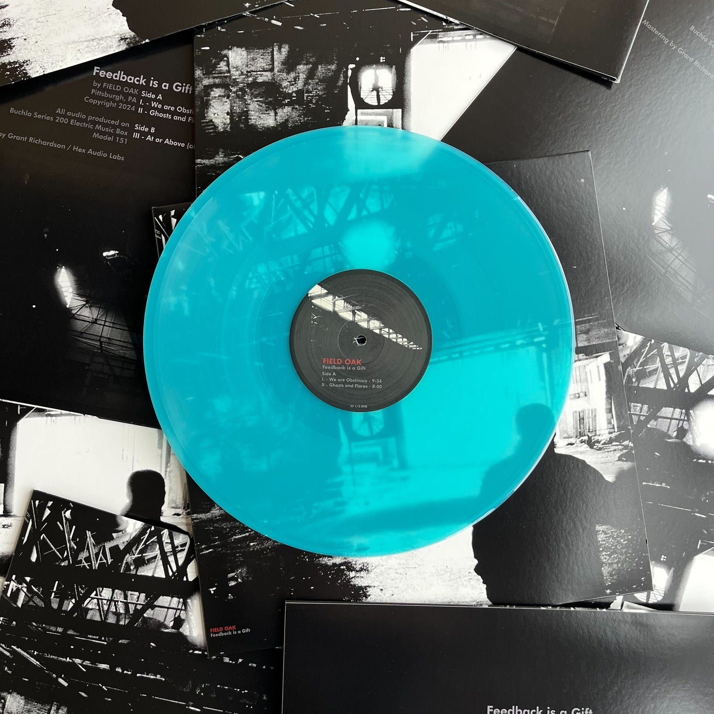 Seaglass blue clear/transparent vinyl record with a black label on a collage of black and white images