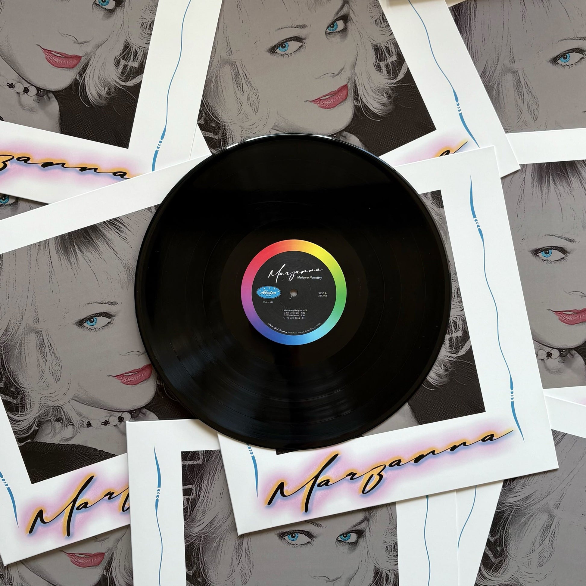 Vinyl record with a colorful label surrounded by Polaroid-style images of a woman's face.